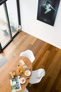 Dining area with a round wooden table and white chairs, featuring a glass of orange juice and a magazine.