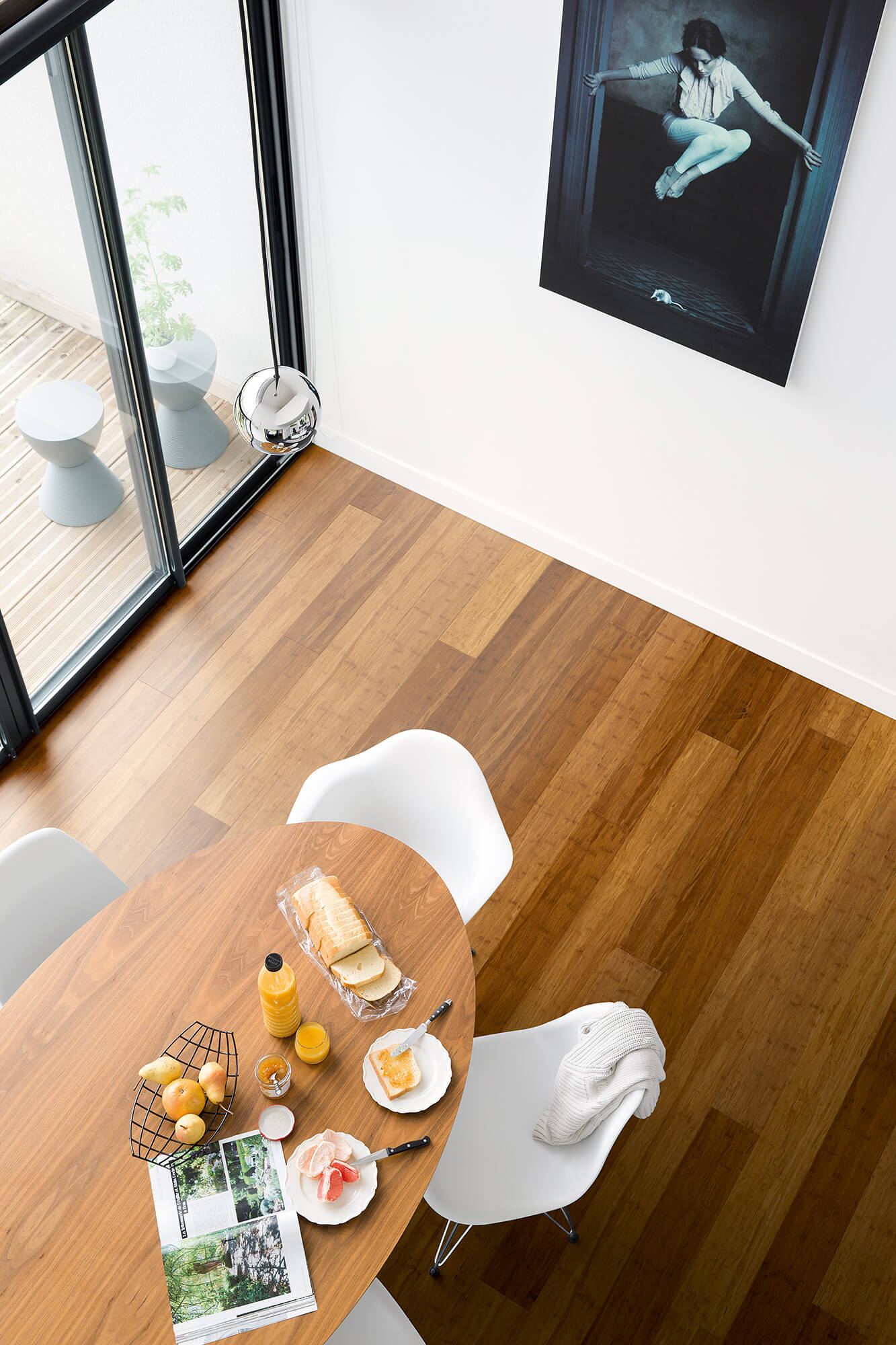 Dining area with a round wooden table and white chairs, featuring a glass of orange juice and a magazine.