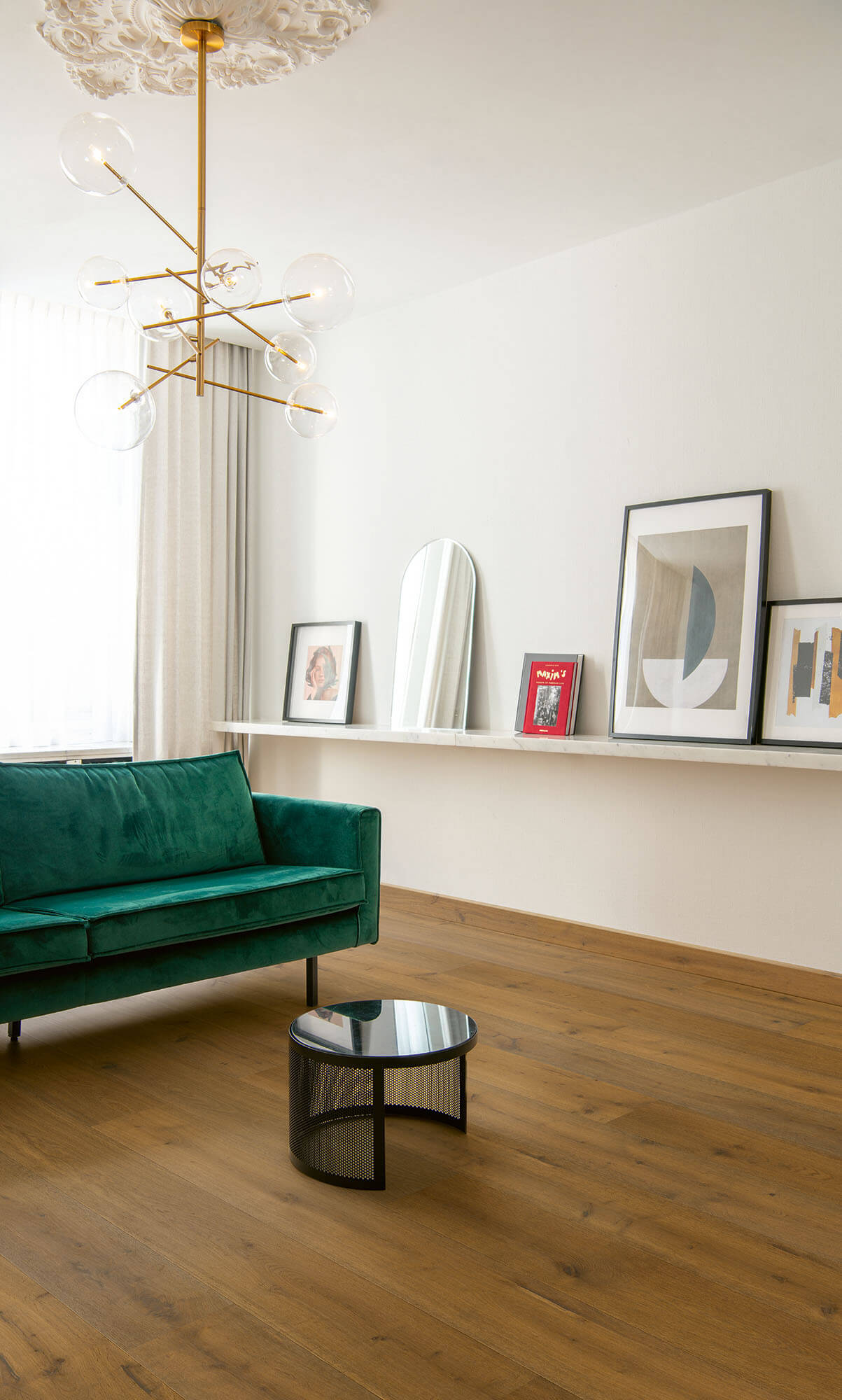 Modern living room with a green sofa, round coffee table, and wall art.
