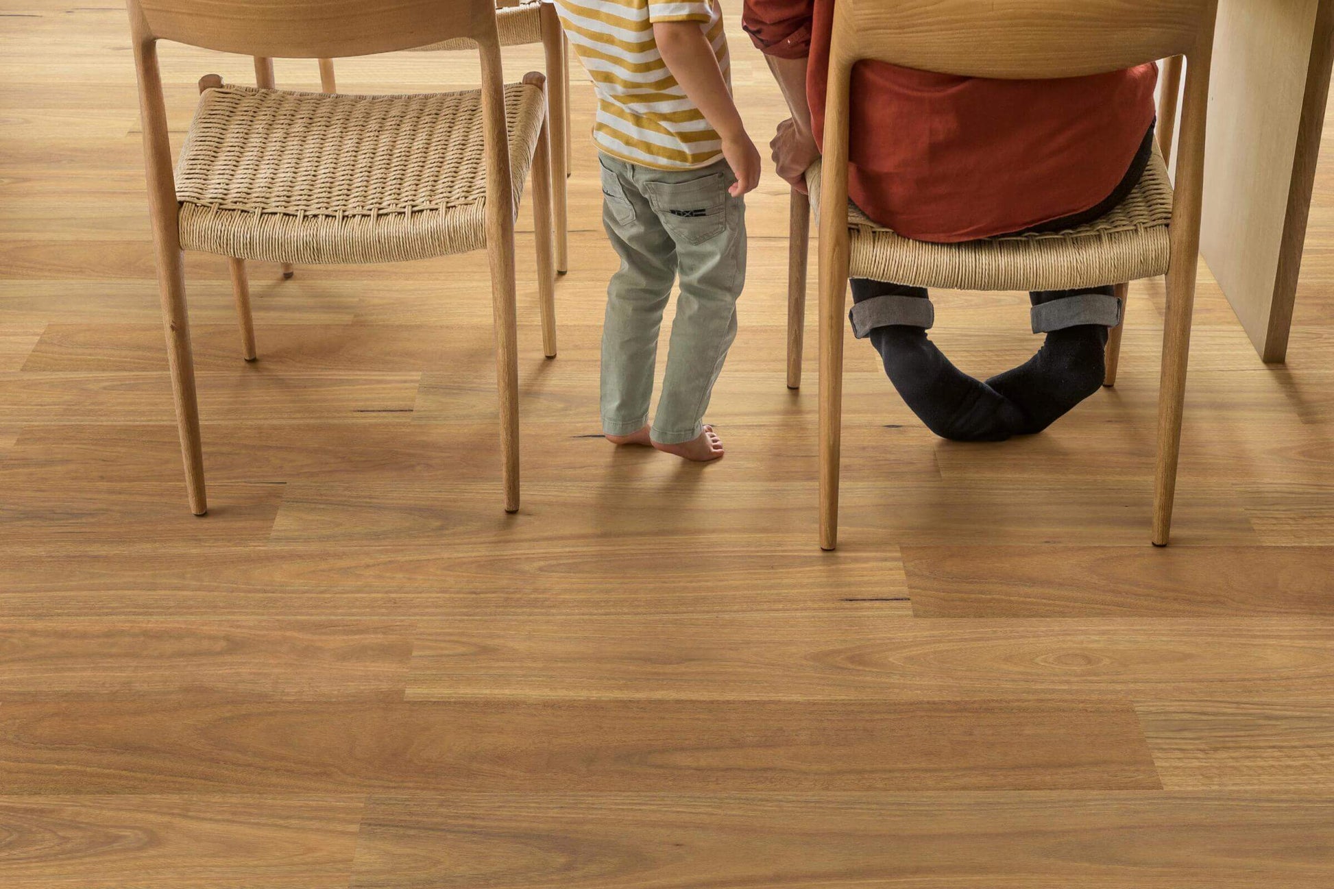 Two people sitting on chairs with a focus on wooden flooring.