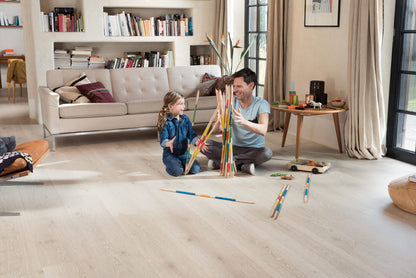 Man and child playing with colorful sticks in a living room.