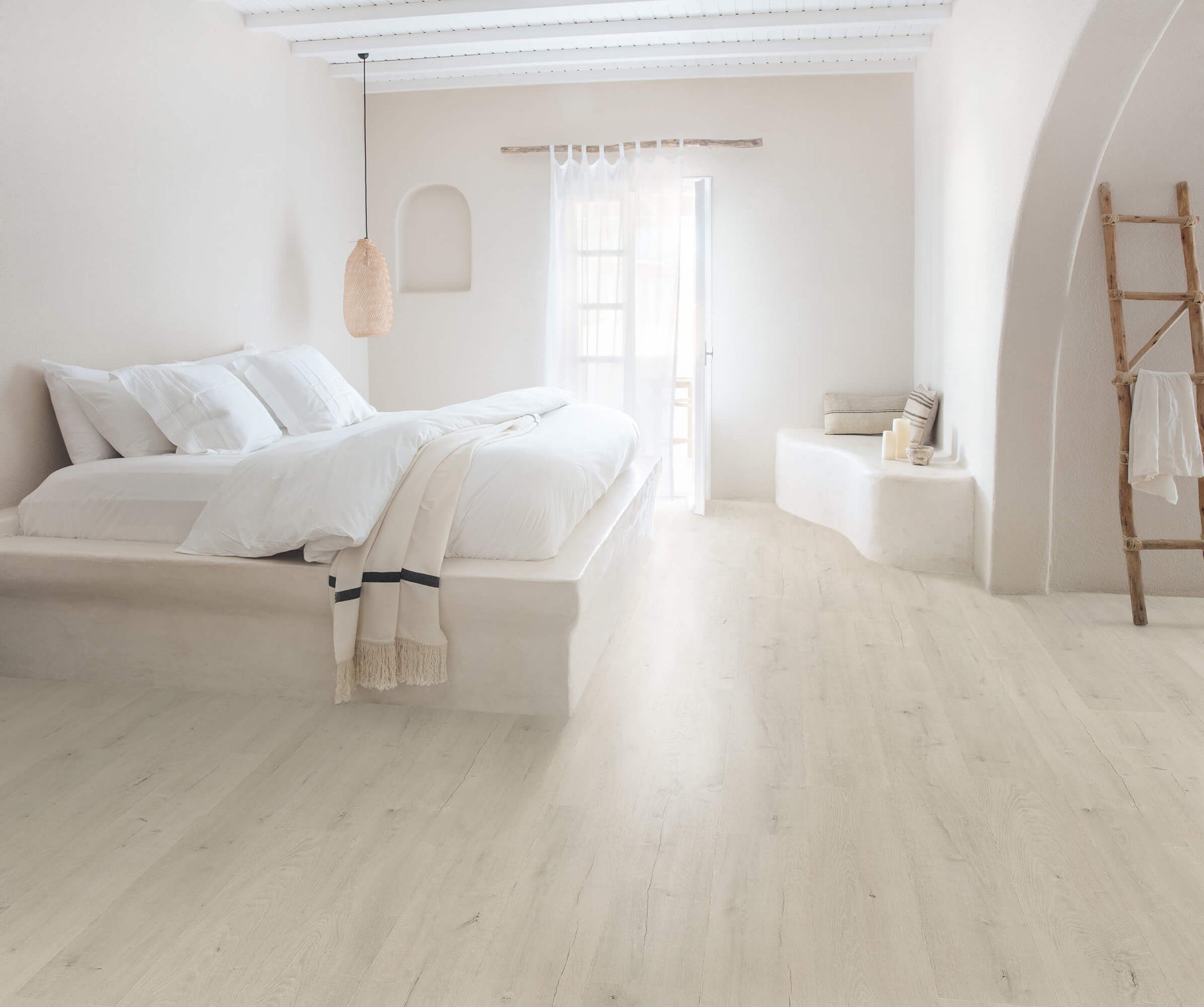 Minimalist bedroom with white walls, bed, and decor.