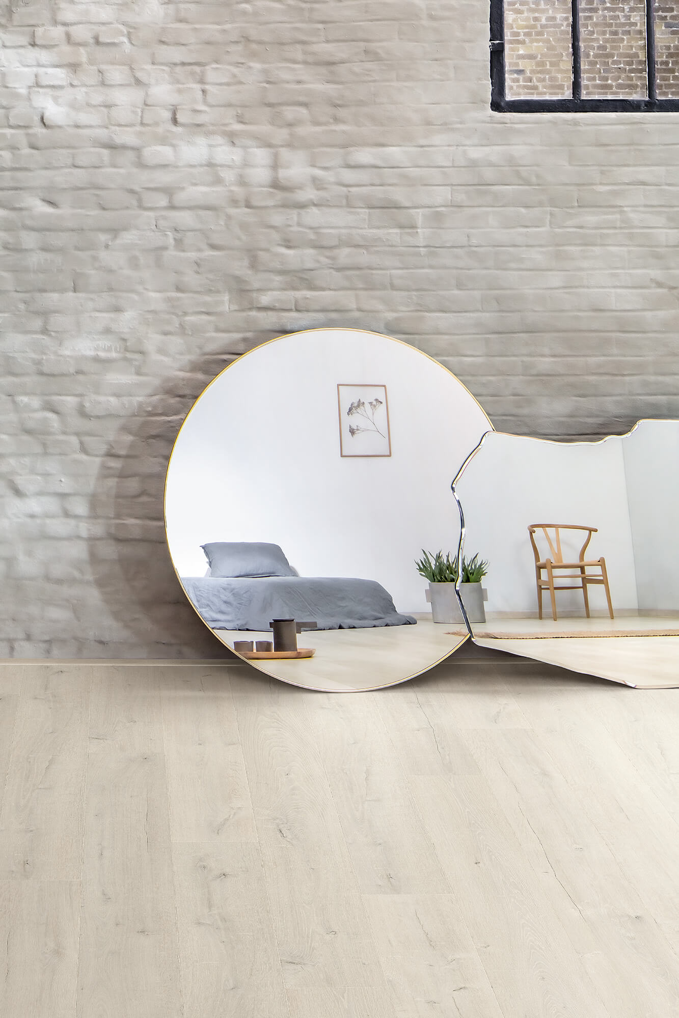 Modern room with a round mirror reflecting a bed and chair against a textured wall.