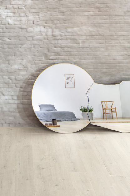 Modern interior design with a round mirror reflecting a bedroom and chair.