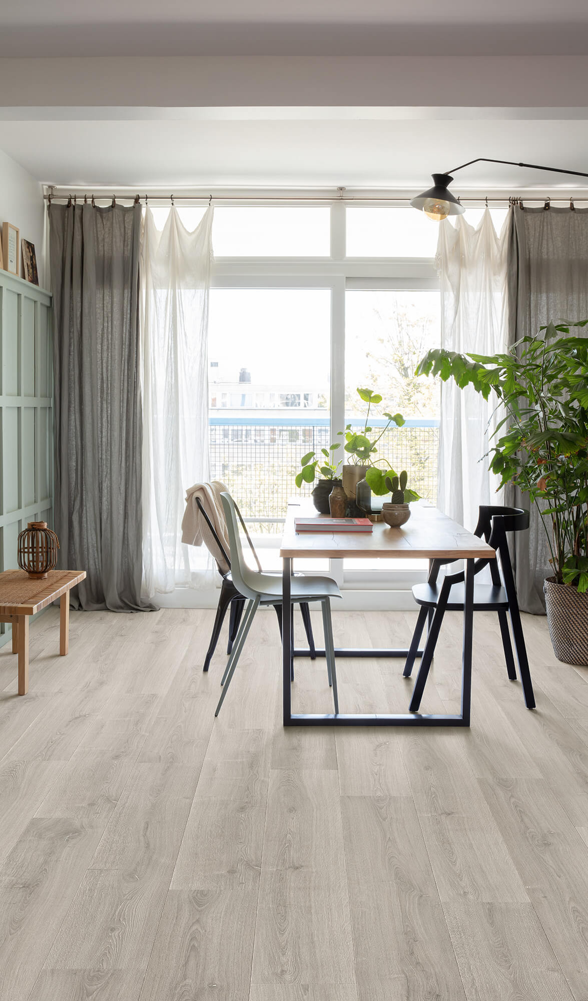 Modern living room with a dining table, chairs, and large windows.