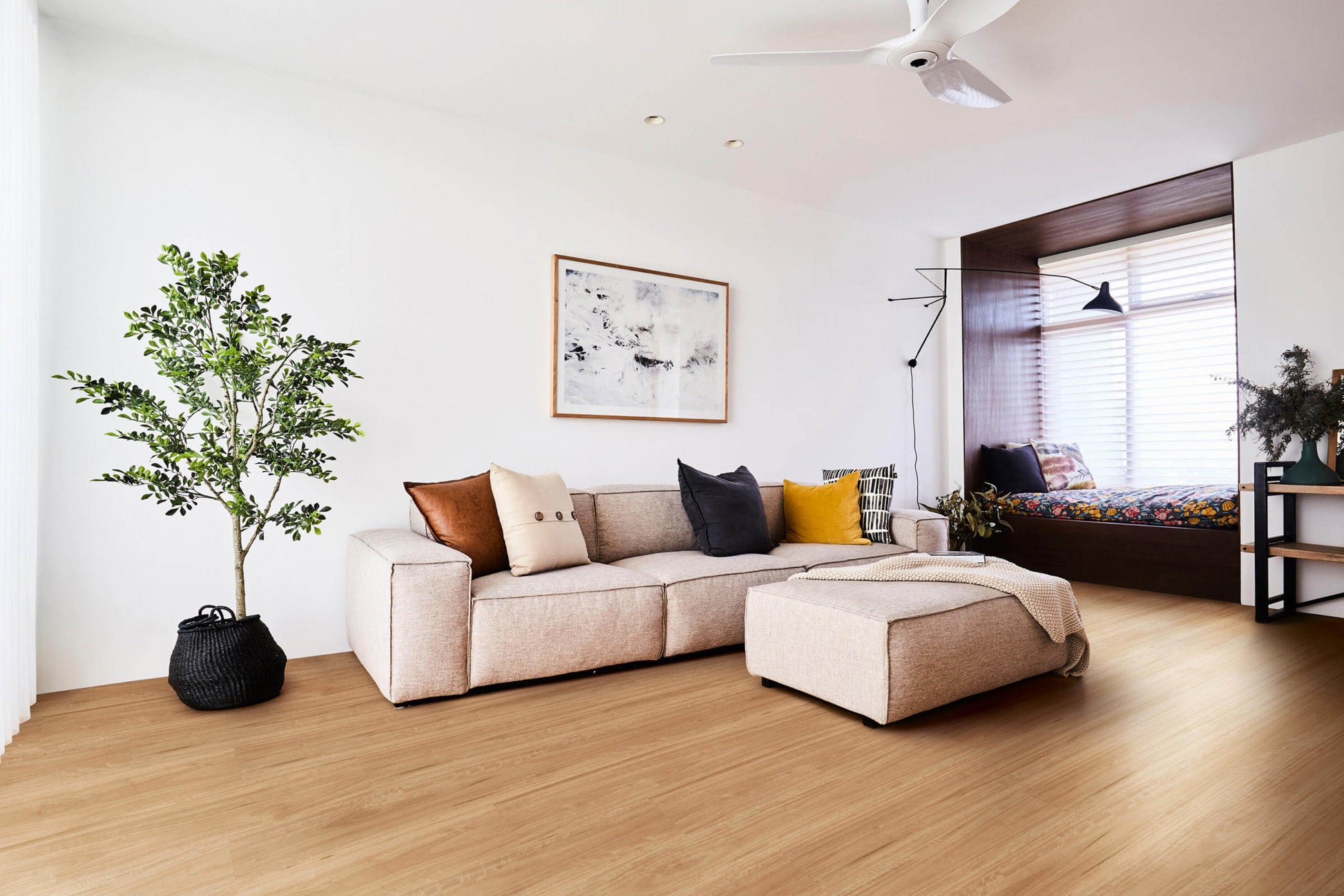 Modern living room with a beige sectional sofa, decorative pillows, and a plant.