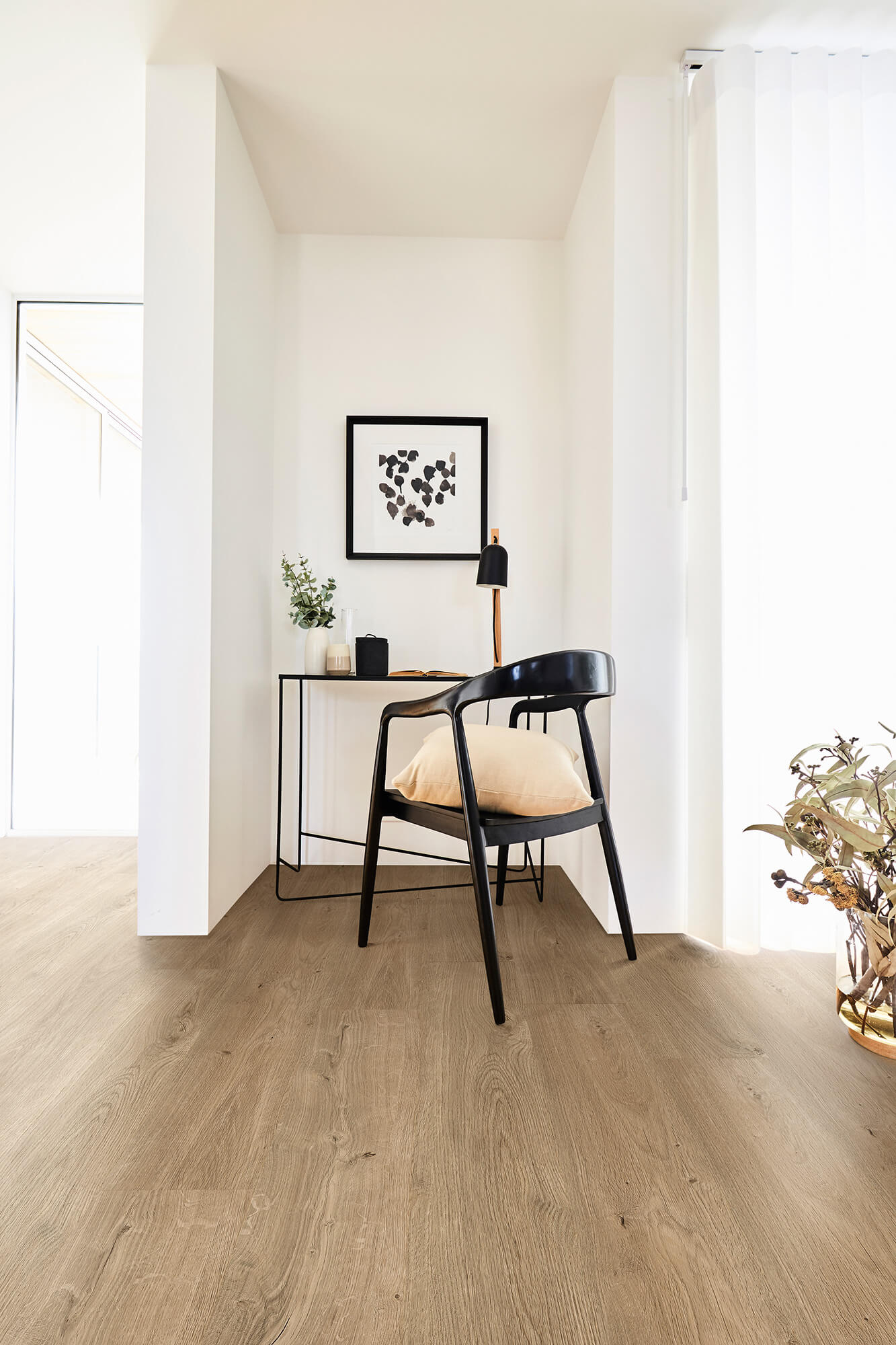 Modern interior with a desk, chair, and decorative items on a wooden floor.