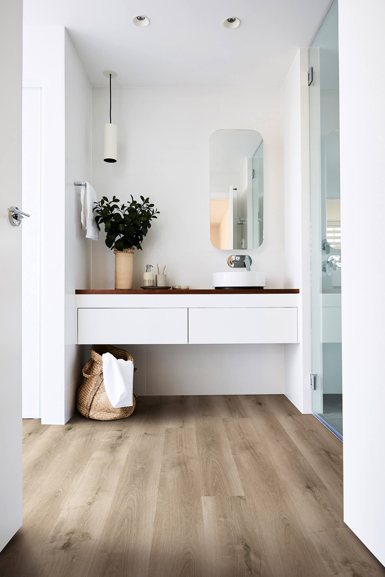 Modern bathroom with wooden vanity, mirror, and plant