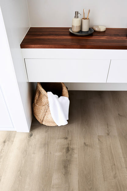 Bathroom vanity with wooden countertop and white cabinets, featuring a basket and towels.